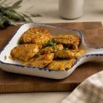 Golden chicken kotleti with corn, cheese, bell pepper, and herbs in a white serving dish